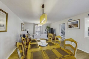A dining area with a table, chairs, and a hanging light fixture. - Lagoon front, 3 story condo w balcony & washer dryer, snowbird-friendly (Hilton Head)