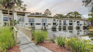 A multi-story hotel with balconies, a water feature, and a wooden deck. - Lagoon front, 3 story condo w balcony & washer dryer, snowbird-friendly (Hilton Head)