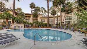 A pool surrounded by lounge chairs, palm trees, and a multi-story building with balconies. - Lagoon front, 3 story condo w balcony & washer dryer, snowbird-friendly (Hilton Head)