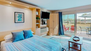 Quarto com cama, televisão, escrivaninha e vista para o exterior.