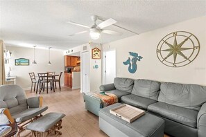 A living room with a grey sofa, a small table, and a ceiling fan. - Coconut Cove: Perfect Location to Beach & Dining! (Sarasota)