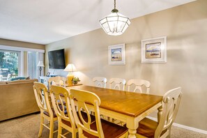 A dining area with a wooden table and chairs, a hanging light fixture, and two framed pictures on the wall. - Family friendly villa with golf course view and seasonally heated complex pool (Hilton Head)