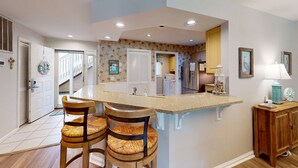 A kitchen with a central island, wooden chairs, a cabinet, and recessed lighting. - Island Bliss Near the Beach with Golf On Site, Shared Pool,Hot Tub & Private Deck (Hilton Head)