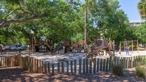 Une aire de jeux avec des structures en bois et une zone délimitée par une clôture.