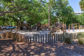 A playground with wooden structures and a fenced area. - Bright & inviting condo near the beach with a private balcony family friendly (Hilton Head)
