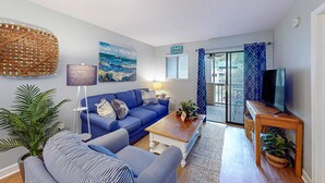 Ein Wohnzimmer mit blauem Sofa, einem gestreiften Sessel und einem Holztisch.