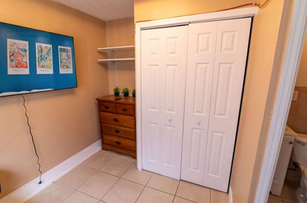 Ein Zimmer mit einem weißen Schrank, einer Holzkommode und einer blauen Wand mit gerahmten Bildern.