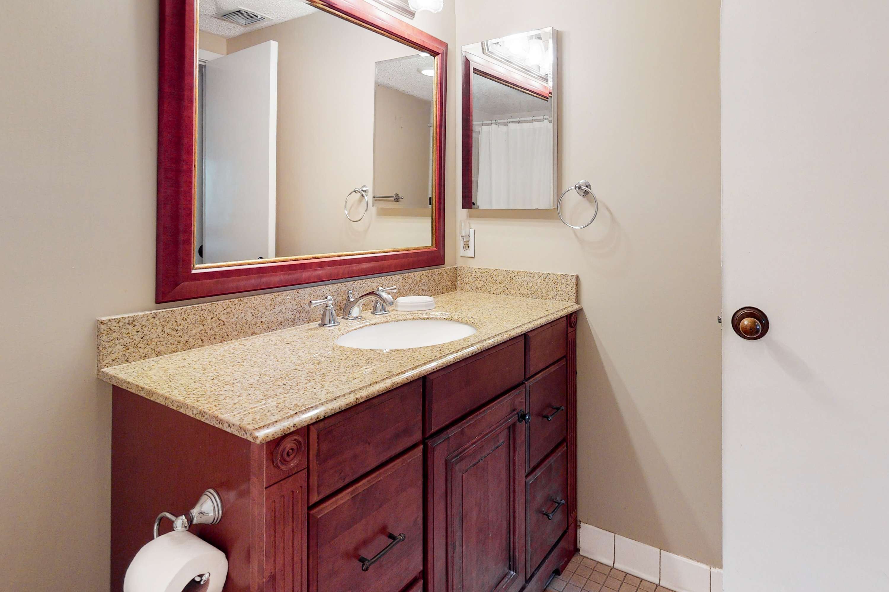A bathroom with a sink, mirror, and wooden vanity.