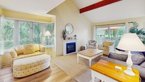 Un salon avec un canapé, une table basse, une cheminée et de grandes fenêtres.