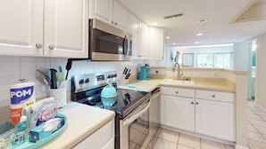 Een moderne keuken met witte kastjes, roestvrijstalen apparatuur en een turquoise aanrechtblad.