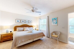 A bedroom with a bed, nightstands, a chair, a ceiling fan, and framed pictures on the wall. - Updated Island Escape with Dual Suites Golf, Tennis, Beach Club, Near Dining (Hilton Head)