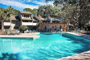 A swimming pool with lounge chairs, a covered area, and buildings in the background. - Harbour Town Stoney Creek Townhouse Balconies, Pool, Golf and Tennis! (Hilton Head)