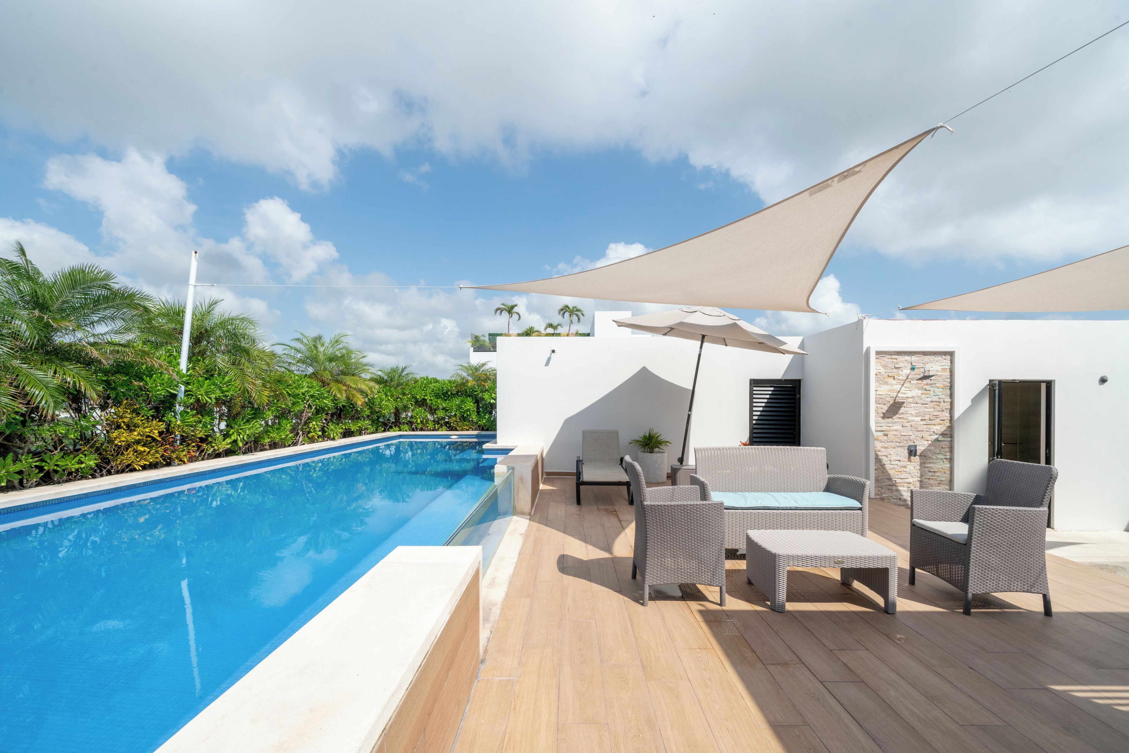 A poolside area with a pool, outdoor furniture, and a white building with a stone facade.
