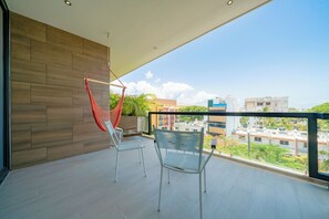 Ein Balkon mit zwei Stühlen, einer Hängematte und Blick auf Gebäude.
