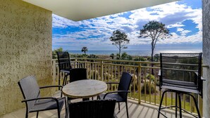 Ein Balkon mit Tisch und Stühlen, Blick aufs Meer und einer Brüstung.
