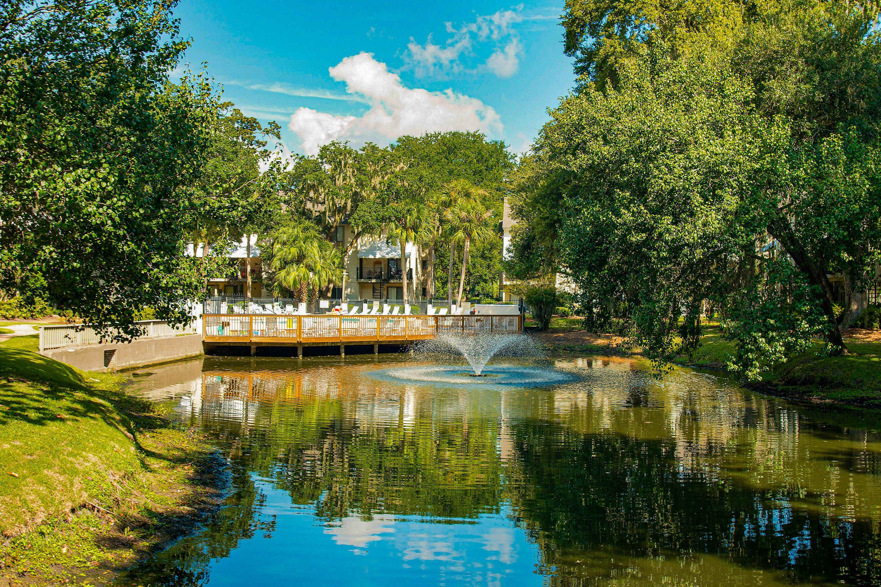 A tranquil park with a fountain, lush greenery, and a gazebo.