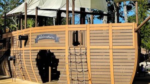 En trælegeplads med navnet 'Adventure', der inkluderer et klatrenet og en rutchebane.