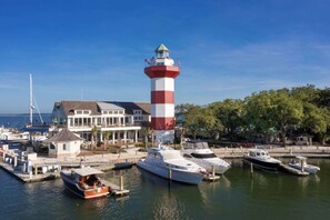 Ein Leuchtturm, ein Yachthafen mit Booten und ein Gebäude mit einem Balkon mit Blick auf das Wasser.