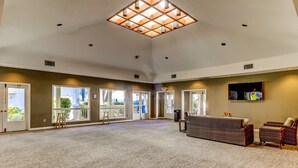 A spacious lobby with a high ceiling, large windows, and a reception area with wicker furniture. - Coastal Condo with Pool, Hot Tub, Tennis, Fast WiFi, AC, & WD, Near the Beach (Hilton Head)