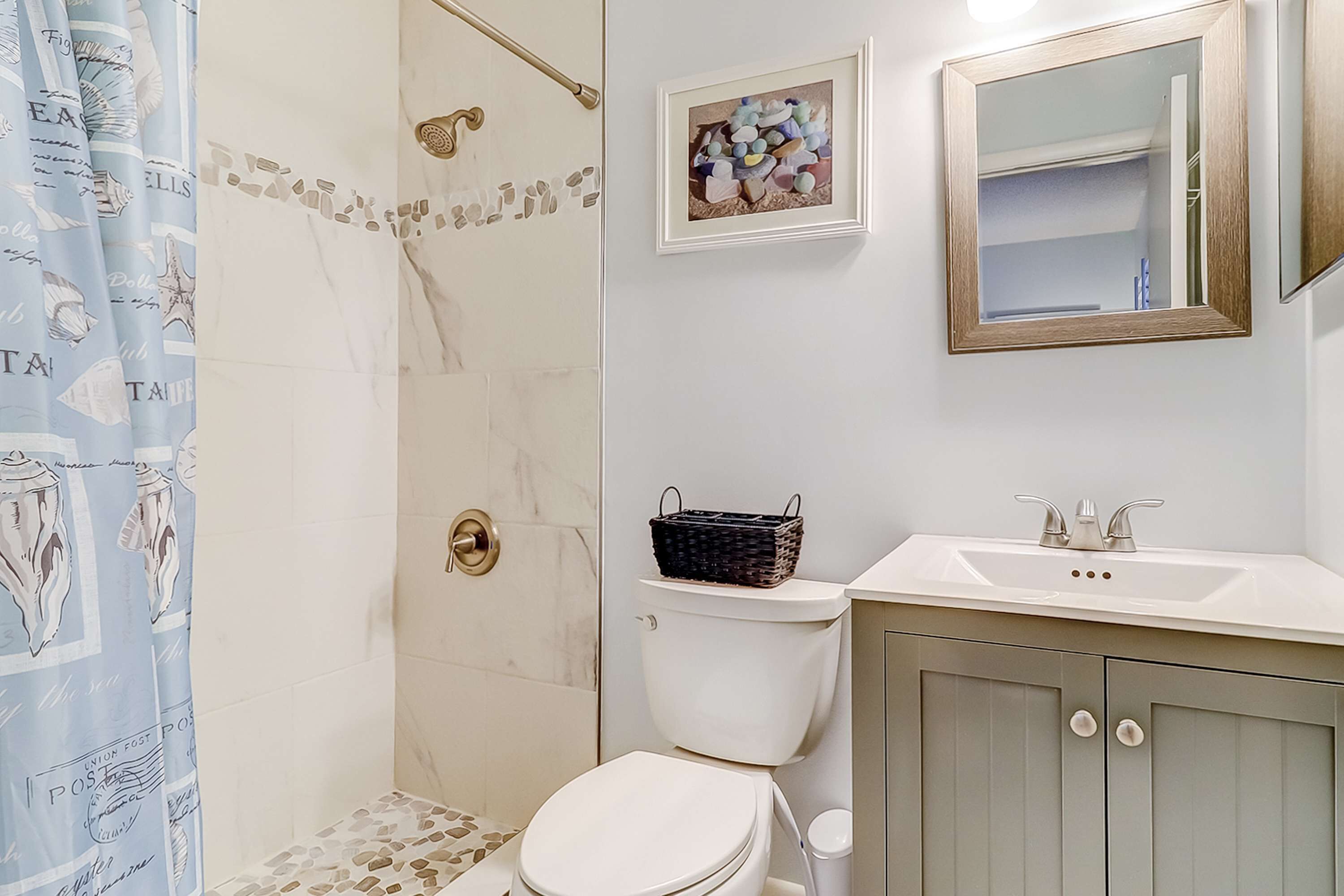 A bathroom with a shower, toilet, sink, and a framed picture on the wall.