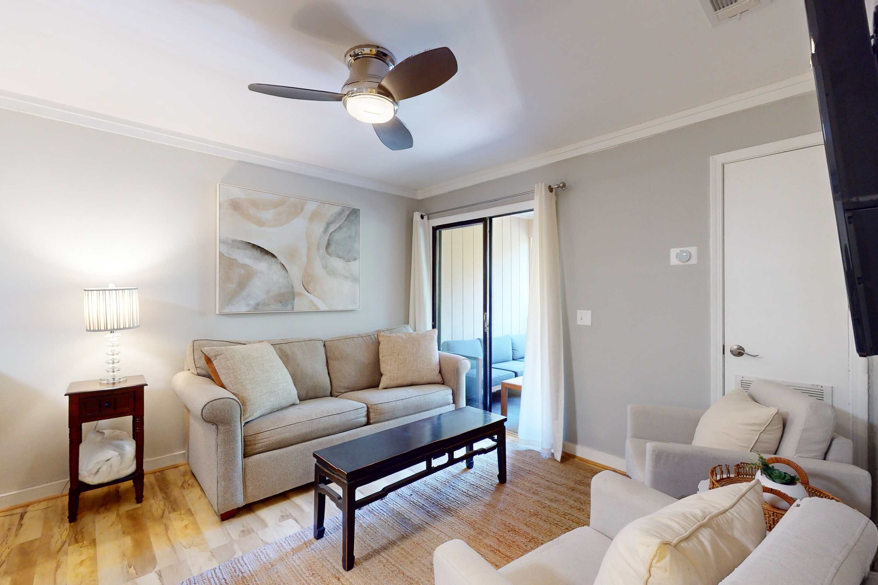 A living room with a sofa, coffee table, and a ceiling fan.