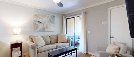 A living room with a sofa, coffee table, and a ceiling fan.