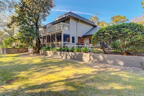 A two-story house with a balcony, a front porch, and a well-maintained lawn. - Comfortable Townhome with WiFi, Screened Porch, Shared Pool and Tennis Court (Hilton Head Island)