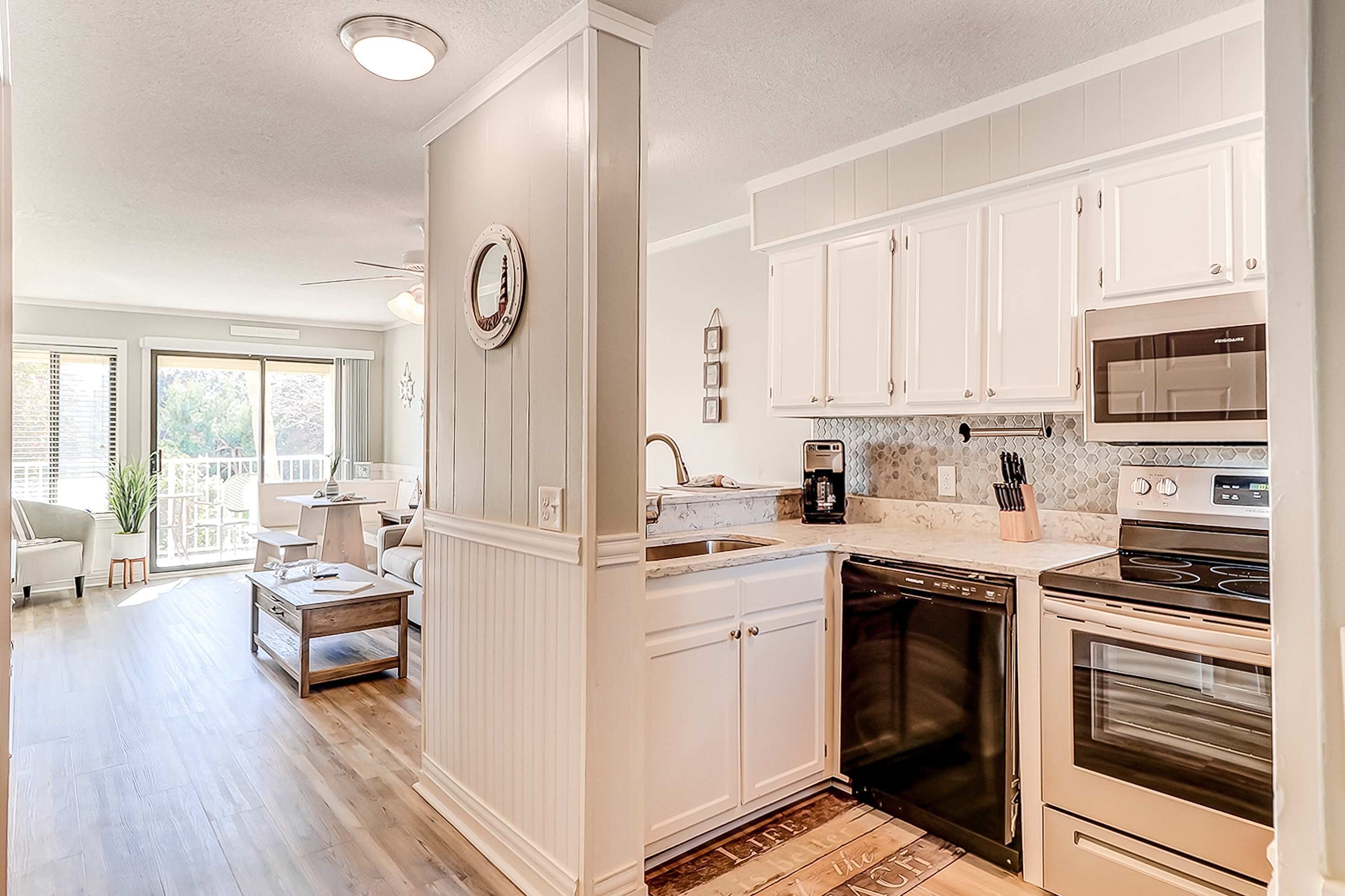 A kitchen with white cabinets, a dishwasher, a stove, and a microwave.