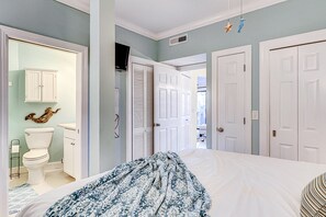 Ein Schlafzimmer mit Bett, einem Kleiderschrank, einem Badezimmer mit Toilette und Waschbecken sowie einem Flur, der in einen weiteren Raum führt.