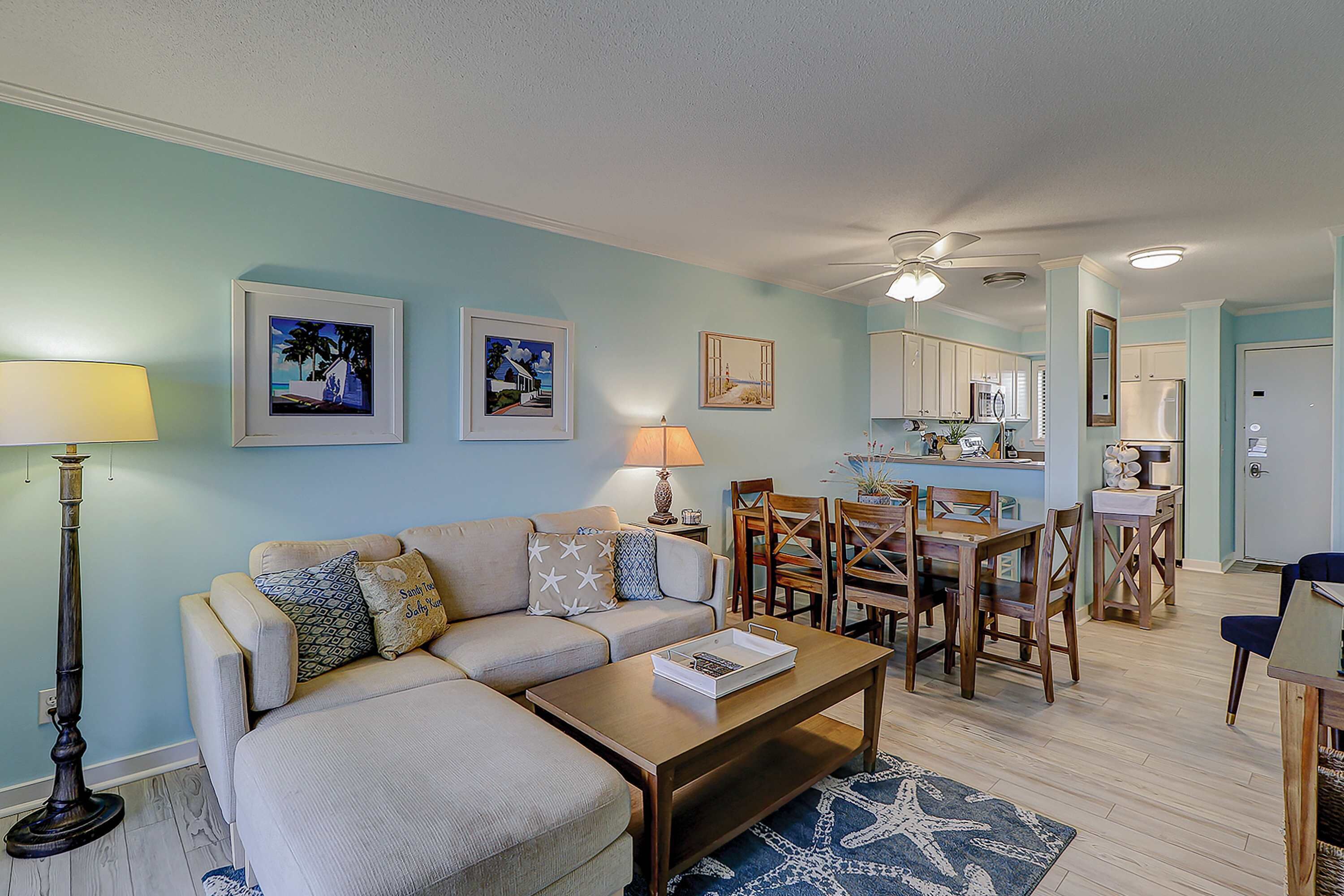 A living room with a sofa, coffee table, and dining area with chairs and a table.