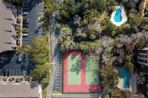 Eine Vogelperspektive eines Wohngebiets mit Tennisplatz, Schwimmbad und Parkplatz.