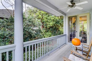 A porch with a white railing, a wooden chair, and a pumpkin decoration. - Sunny & bright home near the beach with private pool & furnished deck (Hilton Head)