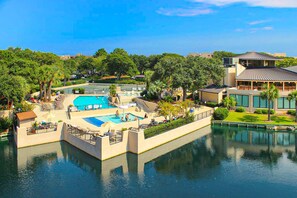 Ein Resort mit einem zentralen Pool, einem separaten Poolbereich und einem Gebäude mit flachem Dach.
