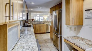 Una cocina moderna con armarios de madera, un refrigerador de acero inoxidable y una encimera de mármol.