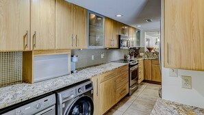 Una cocina moderna con armarios de madera, lavadora integrada y salpicadero de azulejos.