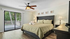 Ein Schlafzimmer mit Bett, Deckenventilator und Blick ins Freie.