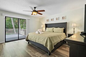 A bedroom with a bed, ceiling fan, and a view to the outside. - Family-friendly condo w/ a furnished deck & shared pools - near golf & shops (Hilton Head)