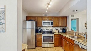 Cocina con electrodomésticos de acero inoxidable, armarios de madera, encimera de granito y microondas integrado.