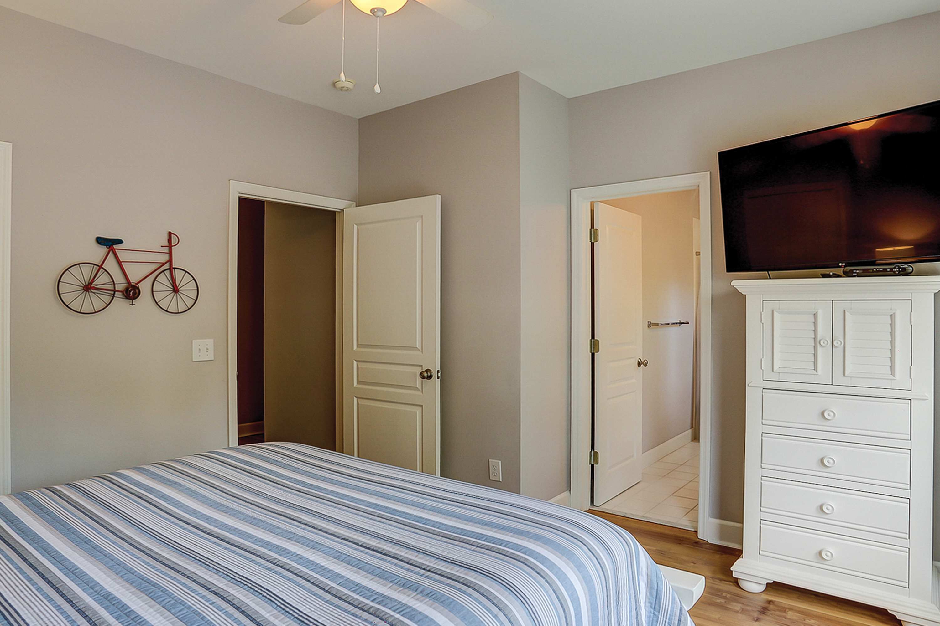 Een slaapkamer met een bed, een televisie op een dressoir en een fiets aan de muur.