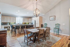 A spacious kitchen with wooden cabinets, a dining table with chairs, and a chandelier.