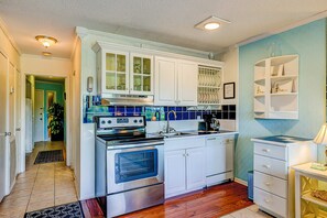 Una cocina con armarios blancos, una estufa y un lavavajillas.