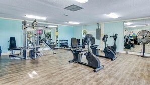 Uma academia com aparelhos de cardio, equipamentos de musculação e um espelho refletindo o espaço.