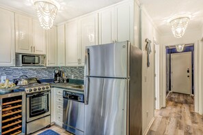 A kitchen with stainless steel appliances, white cabinets, a microwave, and a chandelier. - Ideal island condo with fast WiFi, pool, ocean views, balcony & central AC (Hilton Head)