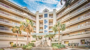 Een hotel met meerdere verdiepingen, een centraal atrium, balkons en palmbomen.