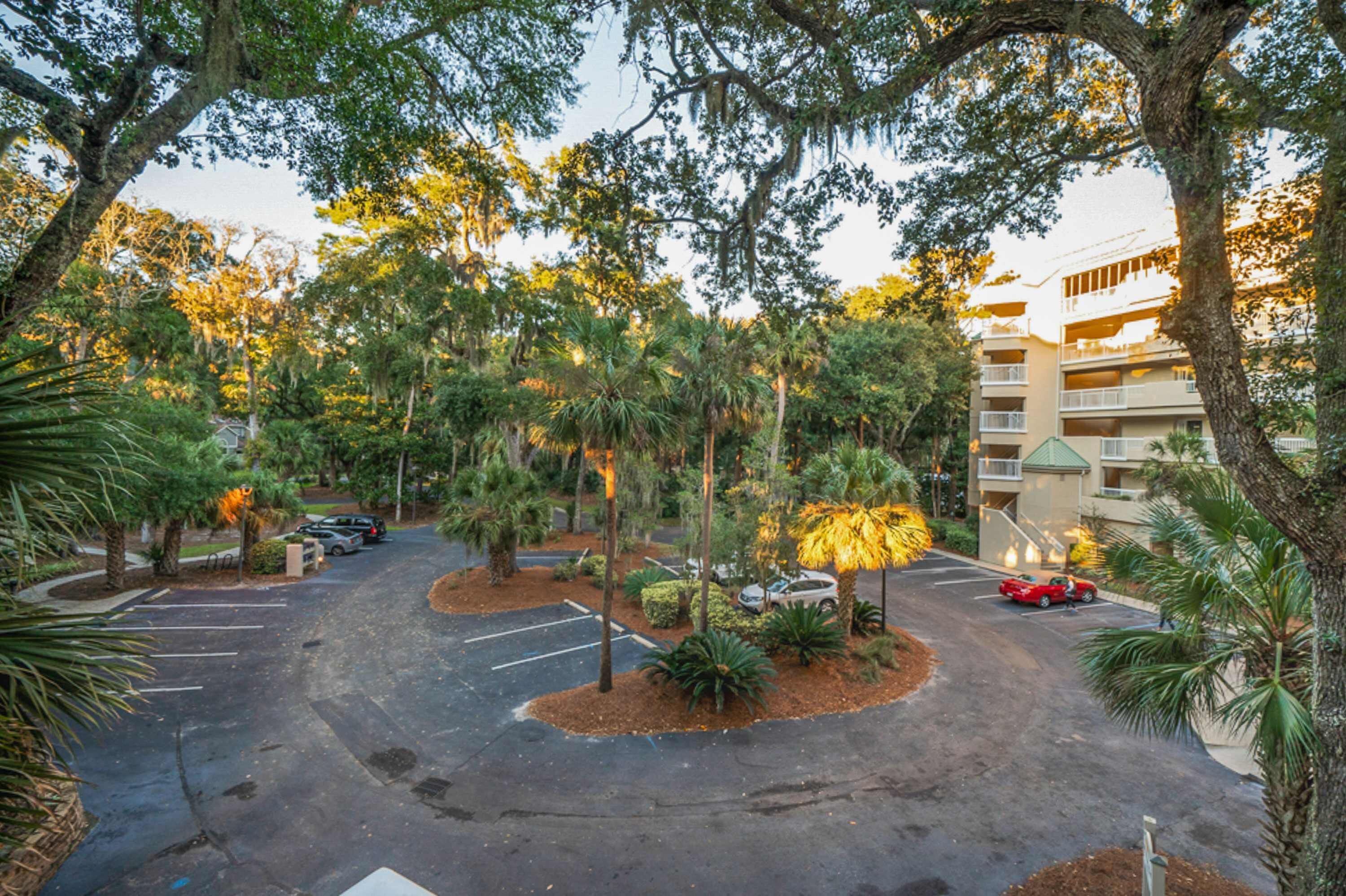 A parking lot with trees and a building in the background.