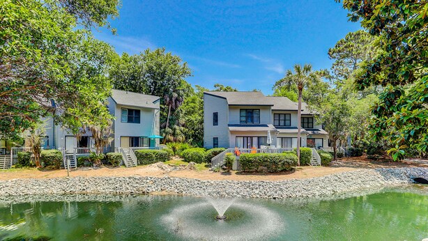 A residential area with a pond, houses, and a fountain. - Dog-friendly island escape near the beach with pool, water view & WiFi (Hilton Head)