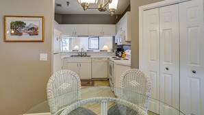 A kitchen with white cabinets, a dining table with chairs, and a chandelier. - Dog-friendly island escape near the beach with pool, water view & WiFi (Hilton Head)