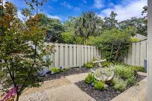 A garden with a wooden fence, various plants, and a decorative anchor. - Relaxing Coastal Escape- Golf course view with shared pool, nearby beach access, and serene island charm (Hilton Head)