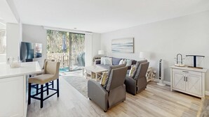 Una sala de estar moderna con un sofá, sillas, un televisor, una mesa de comedor y un aparador.