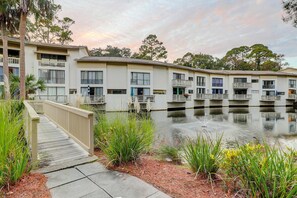 A multi-story building with balconies, a wooden deck, and a water feature. - Lagoon View Villa 2 Pools walk to beach & shops (Hilton Head)